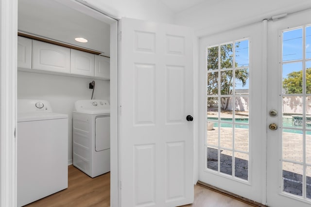 washroom with light wood-type flooring, cabinet space, a healthy amount of sunlight, and washer and clothes dryer