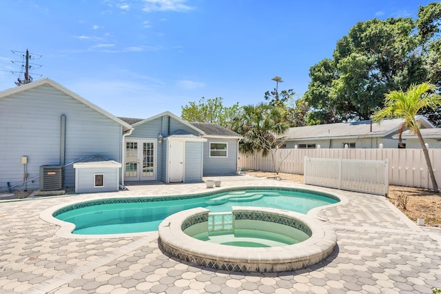 view of pool featuring fence, a patio, a pool with connected hot tub, french doors, and cooling unit