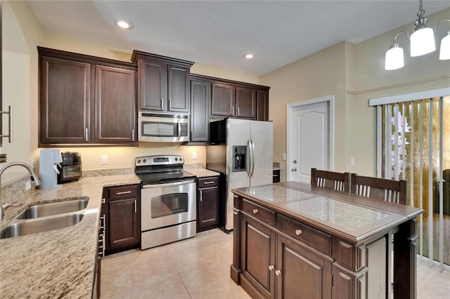 kitchen featuring a kitchen island, dark brown cabinets, a sink, a notable chandelier, and stainless steel appliances