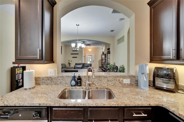 kitchen featuring arched walkways, dark brown cabinetry, and a sink