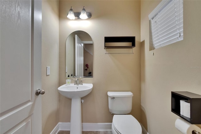 half bathroom featuring toilet and a sink