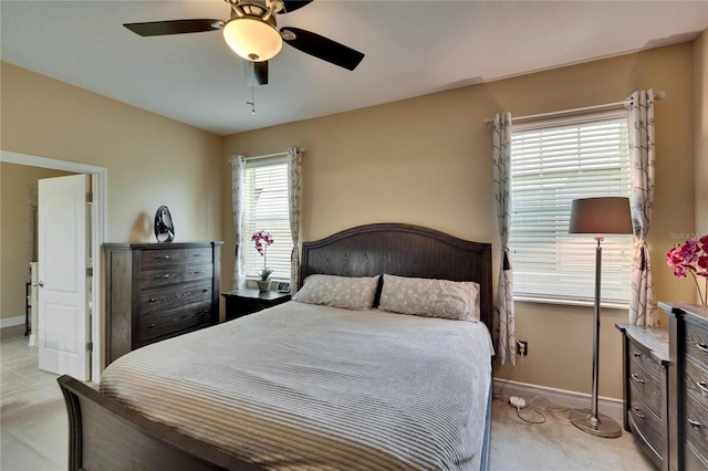 bedroom featuring light colored carpet, baseboards, and ceiling fan