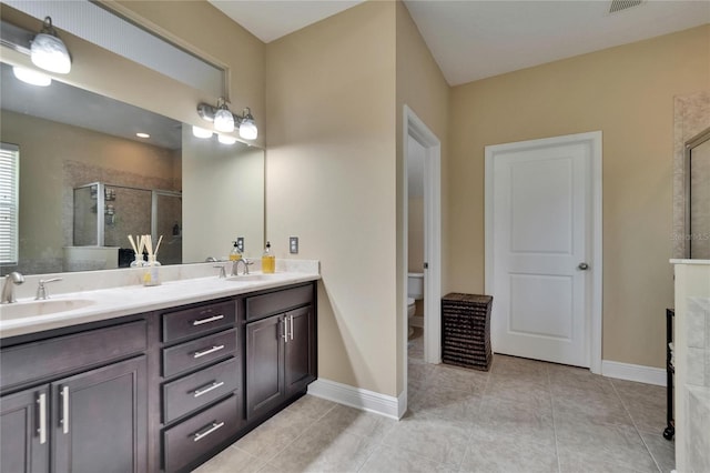 full bath with double vanity, a sink, a stall shower, and toilet