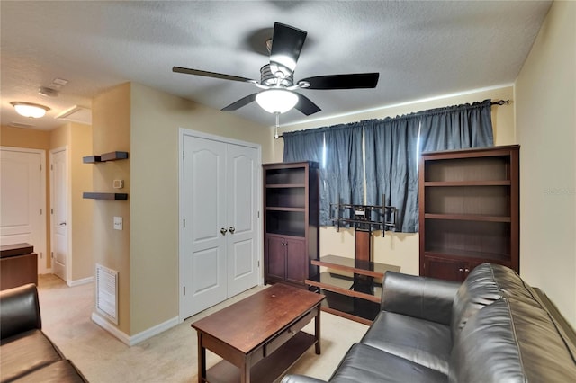 carpeted living room with a textured ceiling, ceiling fan, visible vents, and baseboards