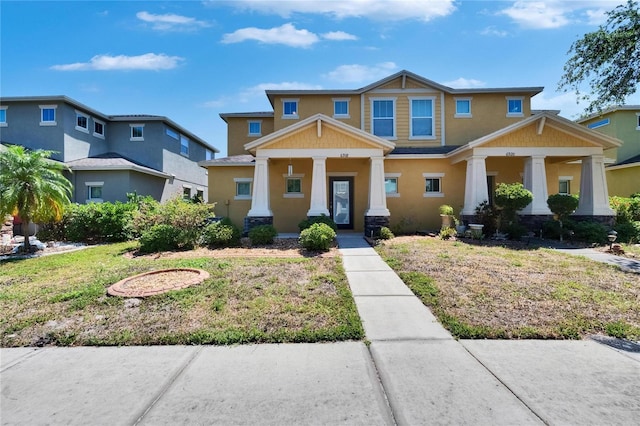 craftsman inspired home featuring stucco siding, a porch, stone siding, and a front yard