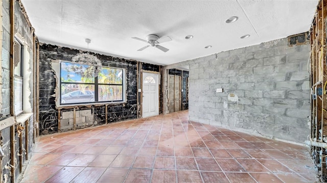 121 86th Ter, Treasure Island, FL 33706 - spare room with a textured ceiling, a ceiling fan, concrete block wall, and tile patterned flooring