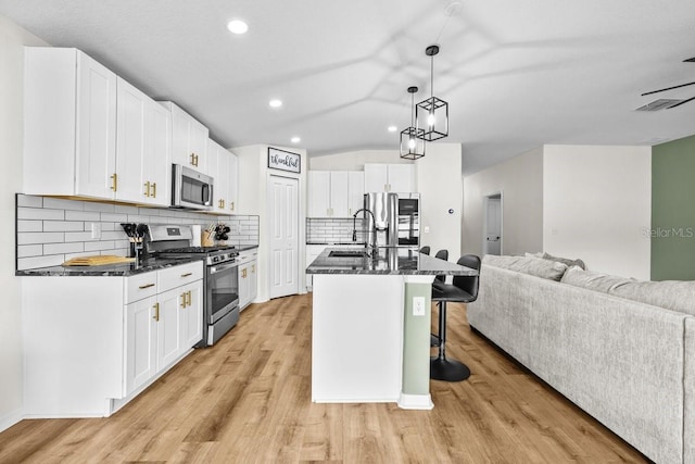 10333 Scarlet Skimmer Dr, Riverview, FL 33578 - kitchen featuring stainless steel appliances, open floor plan, a kitchen breakfast bar, light wood-style flooring, and white cabinetry