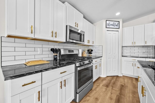 10333 Scarlet Skimmer Dr, Riverview, FL 33578 - kitchen featuring appliances with stainless steel finishes, white cabinetry, dark stone countertops, light wood finished floors, and tasteful backsplash