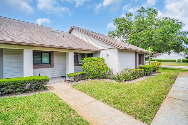 2506 Laurelwood Dr Unit 4C, Clearwater, FL 33763 - view of front of house with a shingled roof, a front lawn, and stucco siding