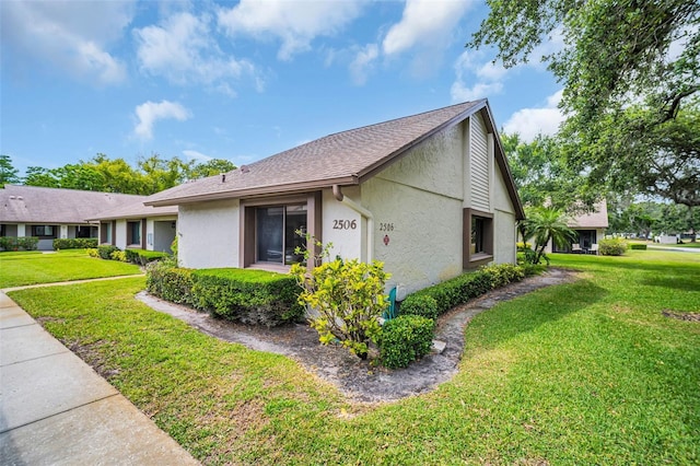 2506 Laurelwood Dr Unit 4C, Clearwater, FL 33763 - view of side of property featuring a lawn, a shingled roof, and stucco siding