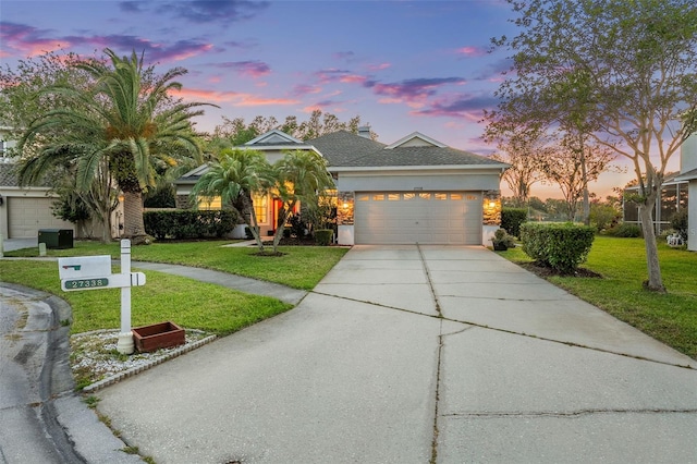 view of front of property with a front yard, driveway, a garage, and stucco siding