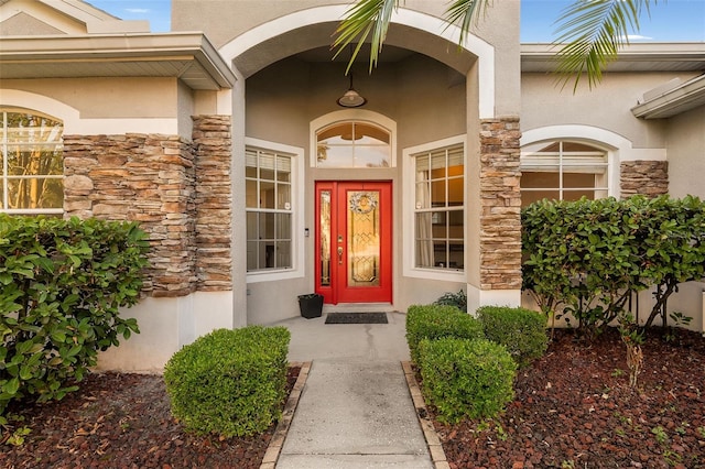 doorway to property featuring stucco siding and stone siding
