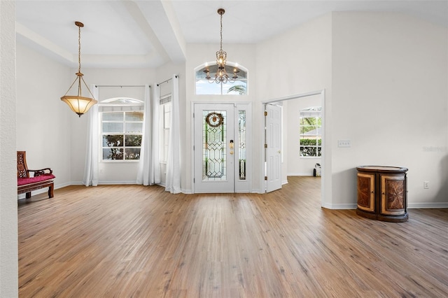 foyer with a high ceiling, a chandelier, wood finished floors, and baseboards