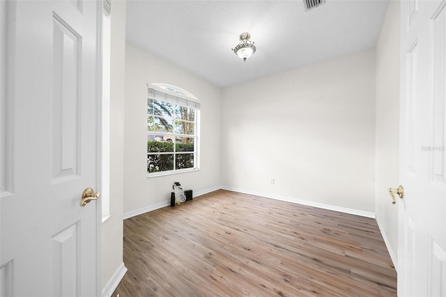 empty room with visible vents, wood finished floors, and baseboards