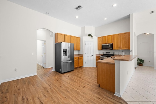 kitchen featuring visible vents, stainless steel appliances, a peninsula, and arched walkways
