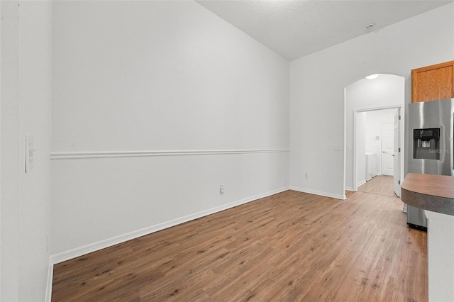 interior space with baseboards, arched walkways, and light wood-style floors