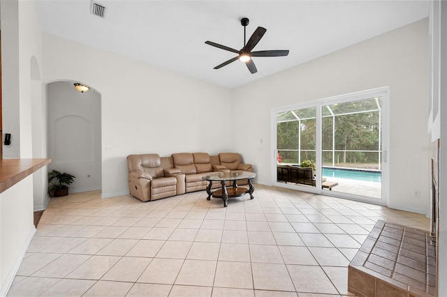 living area with arched walkways, light tile patterned floors, ceiling fan, baseboards, and visible vents
