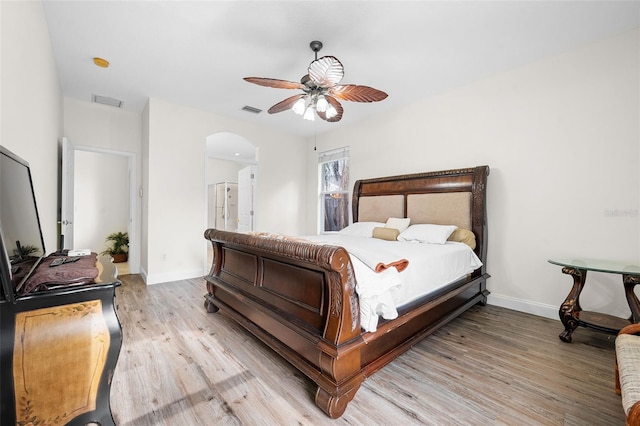 bedroom with light wood-style flooring, visible vents, ceiling fan, baseboards, and arched walkways