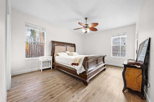 bedroom featuring baseboards, wood finished floors, and multiple windows