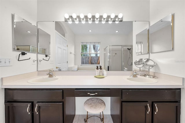bathroom with double vanity, a shower stall, and a sink