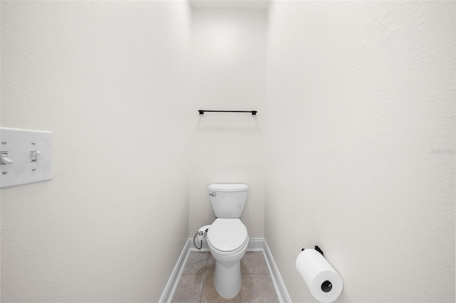 bathroom with toilet, tile patterned flooring, and baseboards