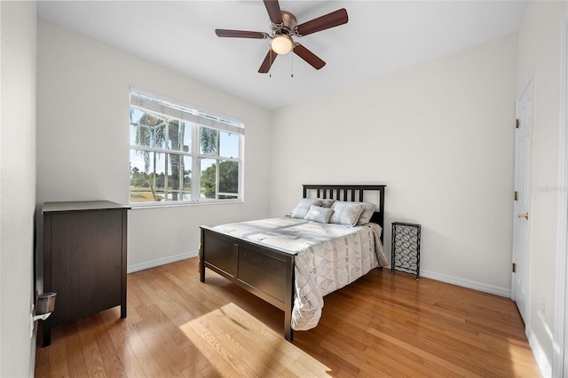 bedroom with a ceiling fan, light wood-style flooring, and baseboards