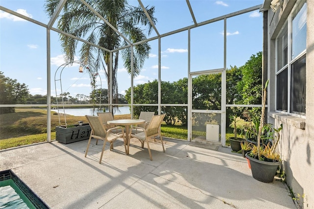 sunroom featuring outdoor dining space and a water view