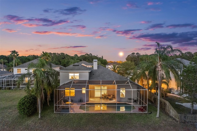 rear view of property featuring stucco siding, a yard, a patio, glass enclosure, and an outdoor pool