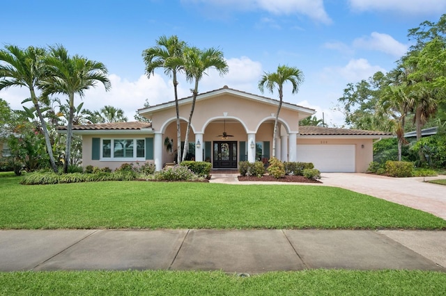 mediterranean / spanish home with a front lawn, stucco siding, driveway, a tiled roof, and an attached garage