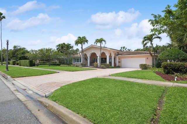 mediterranean / spanish-style house featuring a front lawn, stucco siding, driveway, and an attached garage