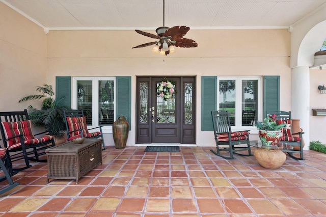 entrance to property with ceiling fan and stucco siding