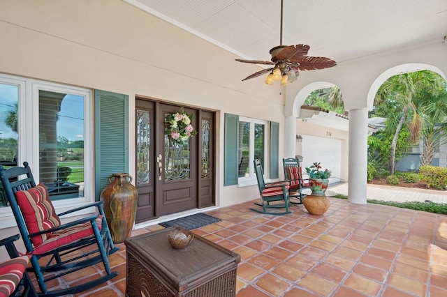 view of patio / terrace with a ceiling fan, a garage, and covered porch