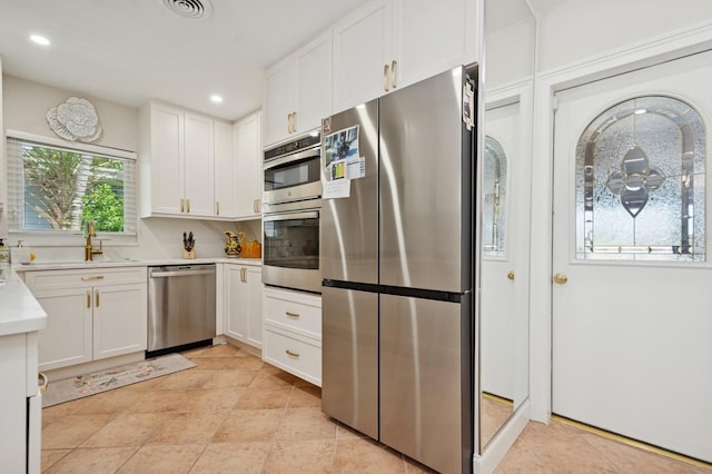 kitchen with recessed lighting, stainless steel appliances, light countertops, a sink, and white cabinetry