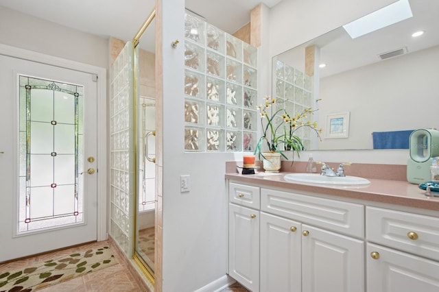 bathroom featuring visible vents, a skylight, a shower stall, and vanity
