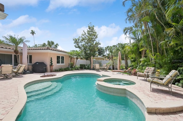 view of pool with fence, a patio area, and a pool with connected hot tub