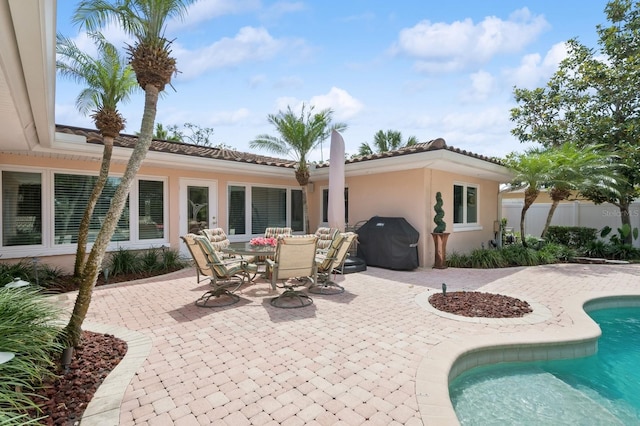 rear view of property featuring fence, stucco siding, an outdoor pool, and a patio area