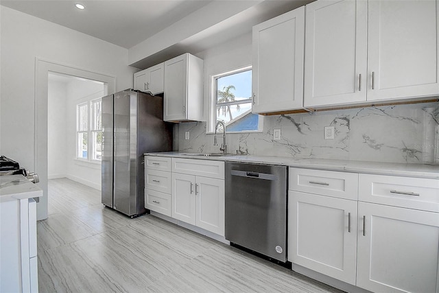 kitchen with appliances with stainless steel finishes, white cabinetry, and a sink