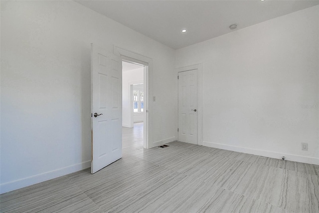 empty room featuring baseboards and recessed lighting