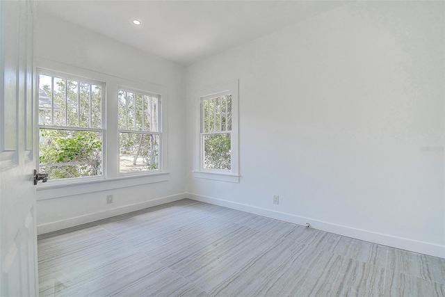 empty room with recessed lighting, wood finished floors, and baseboards