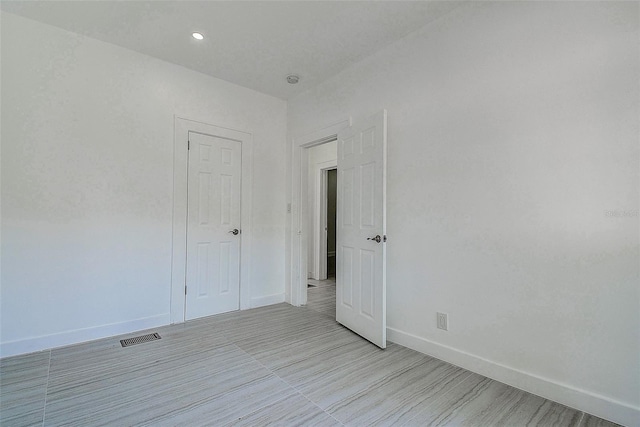 empty room with recessed lighting, visible vents, and baseboards