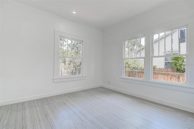 unfurnished room featuring baseboards, wood finished floors, and a healthy amount of sunlight
