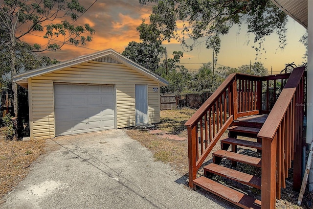 detached garage featuring driveway and fence
