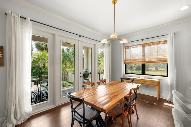 dining space featuring crown molding, dark wood-style flooring, baseboards, and a wealth of natural light