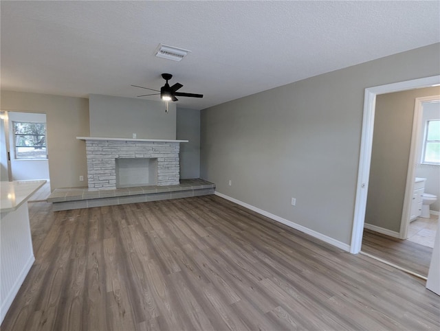 unfurnished living room featuring a ceiling fan, baseboards, visible vents, and wood finished floors