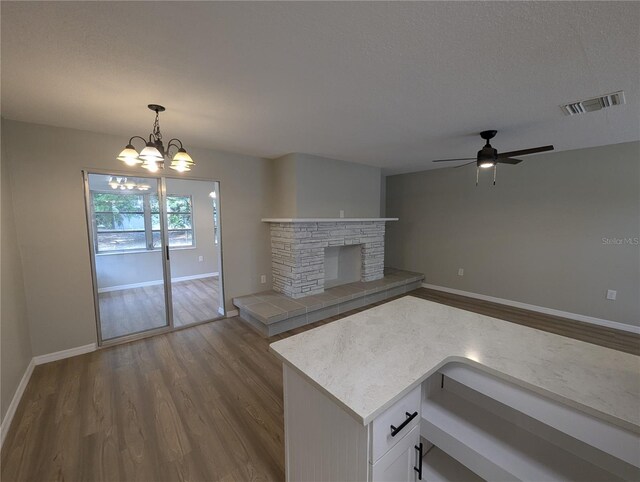 unfurnished living room with visible vents, dark wood finished floors, ceiling fan with notable chandelier, and baseboards