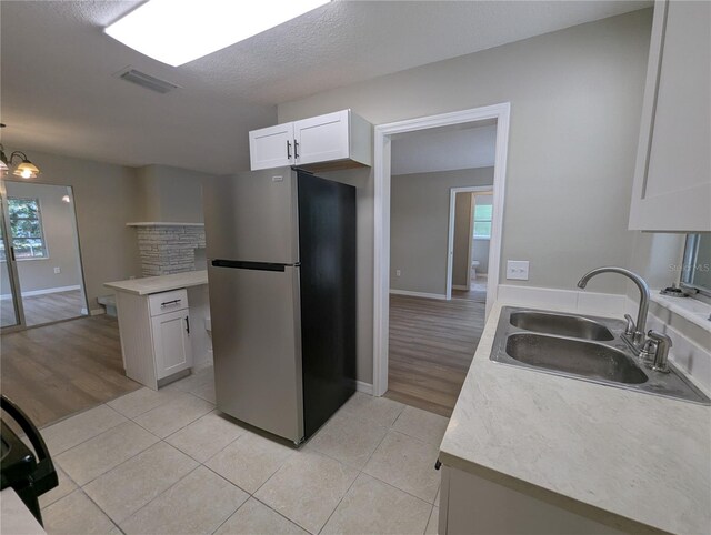 kitchen with visible vents, freestanding refrigerator, a sink, and light tile patterned floors
