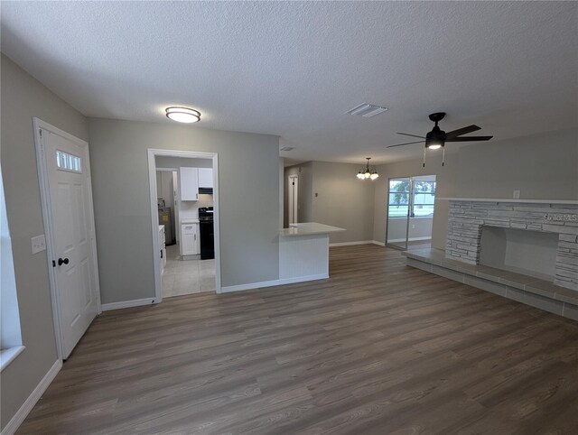 unfurnished living room with a textured ceiling, baseboards, visible vents, and a fireplace