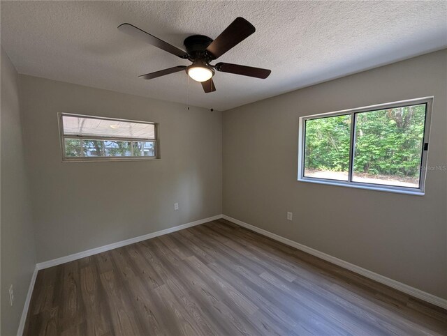 empty room with baseboards, plenty of natural light, and wood finished floors