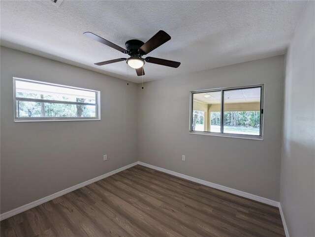 empty room with plenty of natural light, baseboards, and dark wood-type flooring
