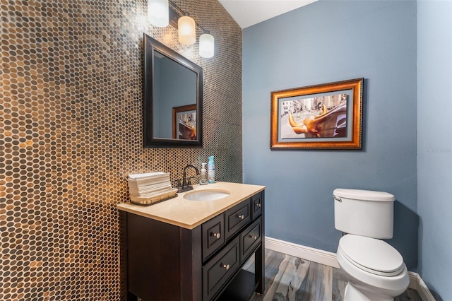 bathroom with baseboards, wood finished floors, toilet, and vanity